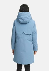 Chaqueta azul claro con capucha, con un diseño de espalda dividida, cintura elástica y letras bordadas en el cuello. Textura suave.