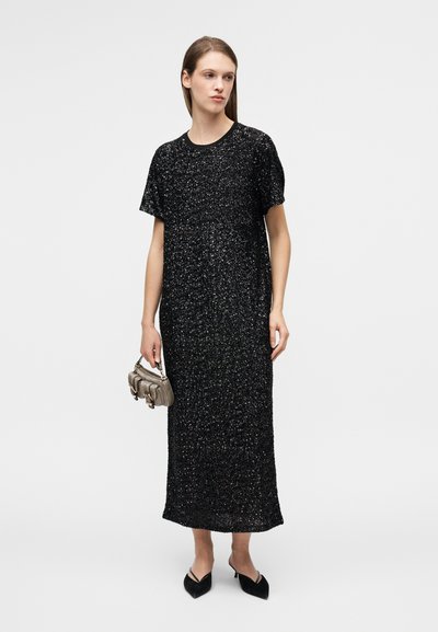 Μαύρο, λαμπερό μίντι φόρεμα με κοντά μανίκια και στρογγυλή λαιμόκοψη. Διαθέτει χαλαρή εφαρμογή και υφή στο ύφασμα. Συνδυασμένο με υφασμάτινη τσάντα.