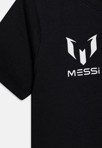 Juodas medvilnės marškinėlis su apvalia iškirpte. Papuoštas baltu grafiniu logotipu, kuriame pavaizduoti stilizuoti ragai ir žodis "MESSi."
