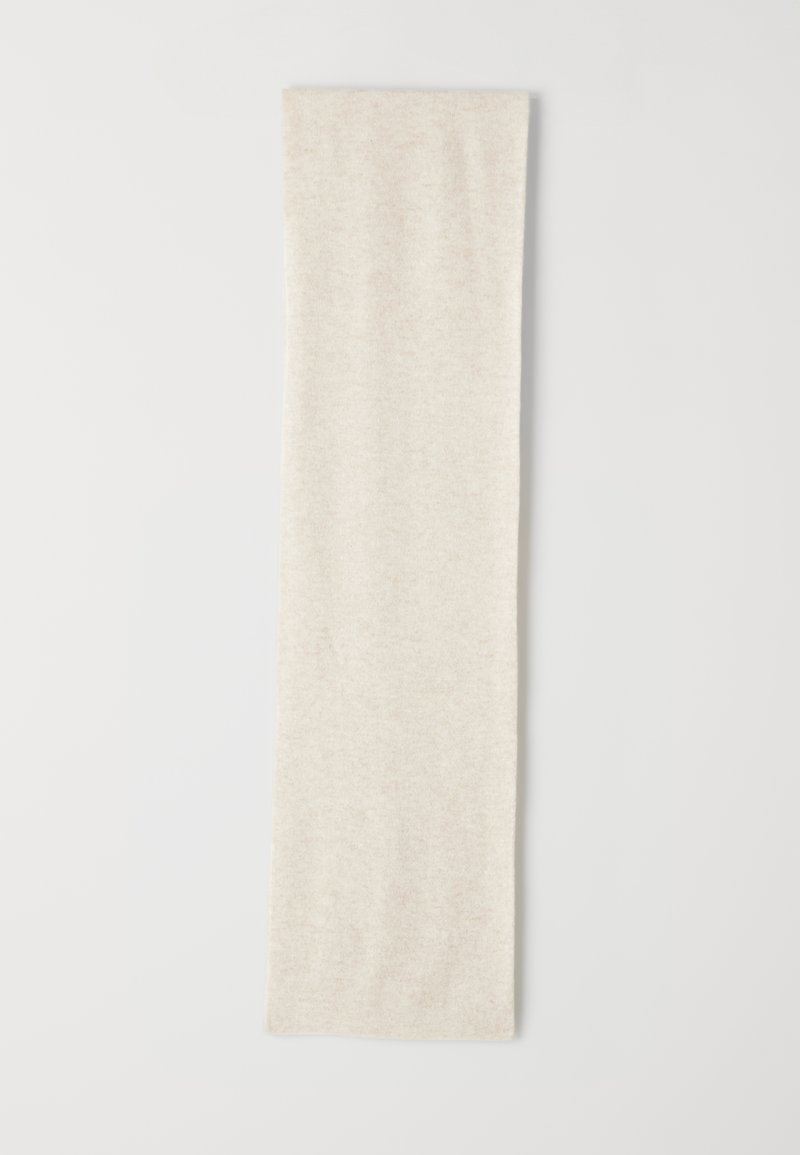 Lunga sciarpa beige in maglia stesa su una superficie bianca, che mostra un tessuto morbido e testurizzato senza pattern o decorazioni visibili.