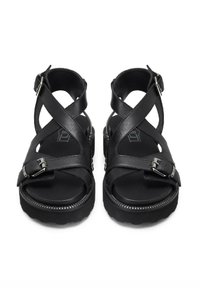 Sandali in pelle nera con cinturini incrociati, fibbie regolabili e suola in gomma texture. Design a punta arrotondata e dettagli cuciti.