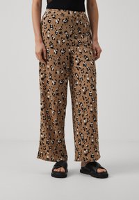 Bredde bukser i brunt med et svart-hvitt leopardmønster, med en glatt tekstur og elastisk midje.