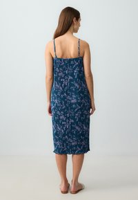Ärmelloses, knielanges Kleid mit einem blauen Blumenmuster, mit Falten und einem Rüschensaum, aus leichtem Stoff gefertigt.