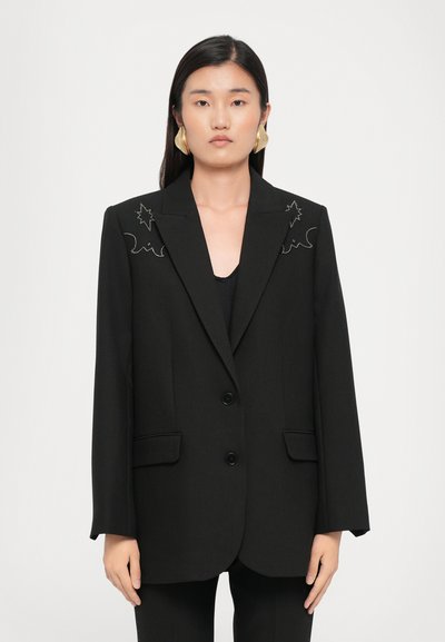 Schwarzer Blazer mit Reverskragen, zwei Knöpfen und einzigartigen bestickten Akzenten an den Schultern. Das Material wirkt glatt und maßgeschneidert.