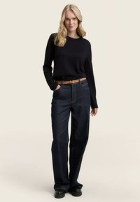 Ciemnoniebieskie dżinsy o prostych nogawkach, zestawione z czarnym topem z długim rękawem i brązowym skórzanym paskiem, noszone z czarnymi butami.