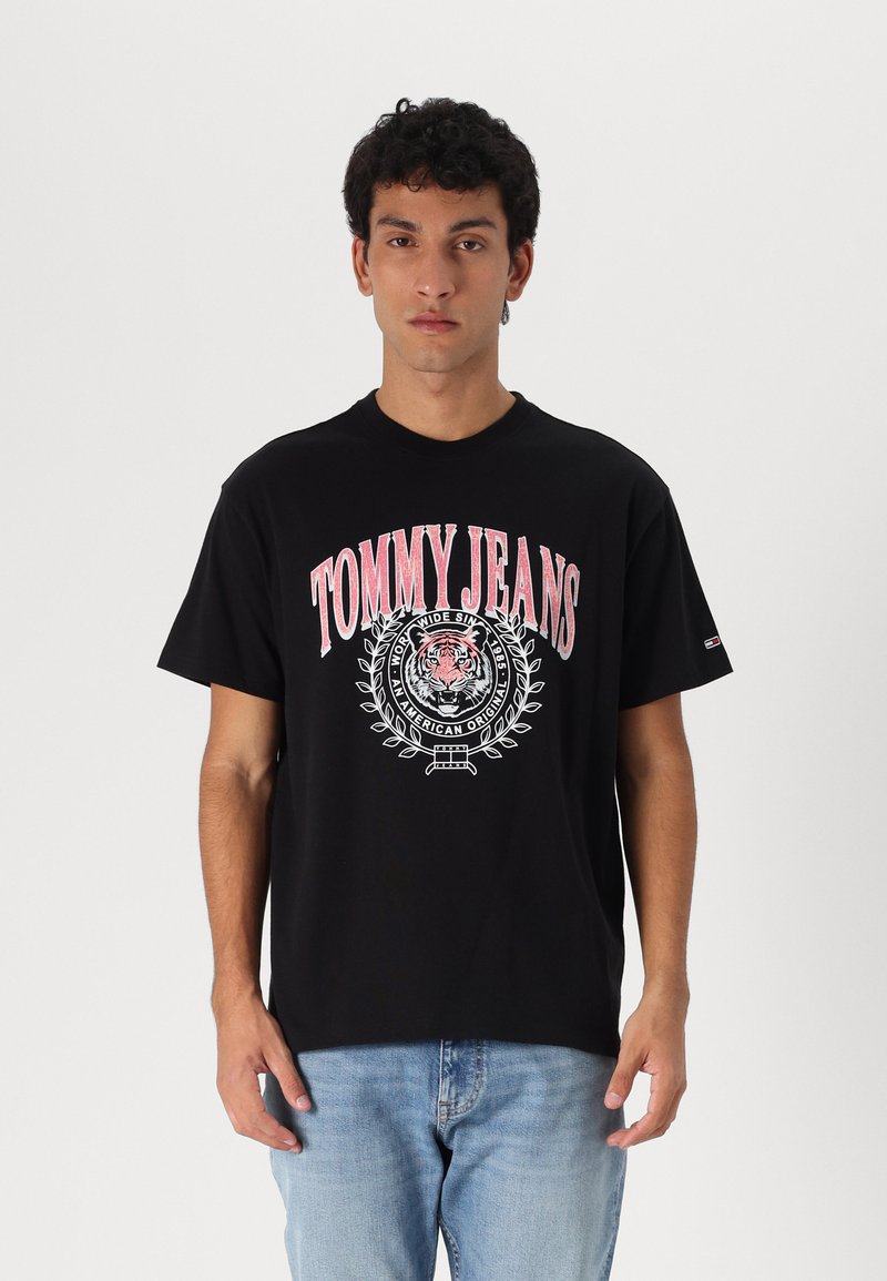 Must must kevad T-särk, millel on punane ja valge "TOMMY JEANS" graafika koos tiigri kujunduse ja lauri aktsentidega, lühikesed varrukad ja vabalt istuv lõige.