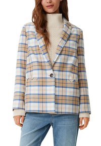 Blazer a cuadros en tonos marrones y azules, con un diseño estructurado, solapas de muesca y dos bolsillos frontales. Usado sobre un suéter texturizado color crema.