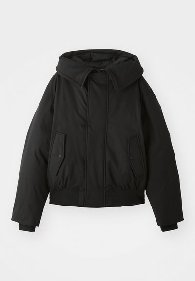 Giacca nera imbottita con colletto alto, chiusura con zip, tasche laterali doppie, polsini elasticizzati e orlo corto. Texture liscia e opaca.