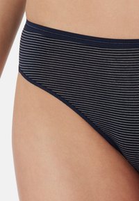 Parte inferiore di bikini blu navy con sottili strisce bianche orizzontali. Caratterizzata da un ampio elastico in vita e da una texture liscia e morbida. Taglio classico.