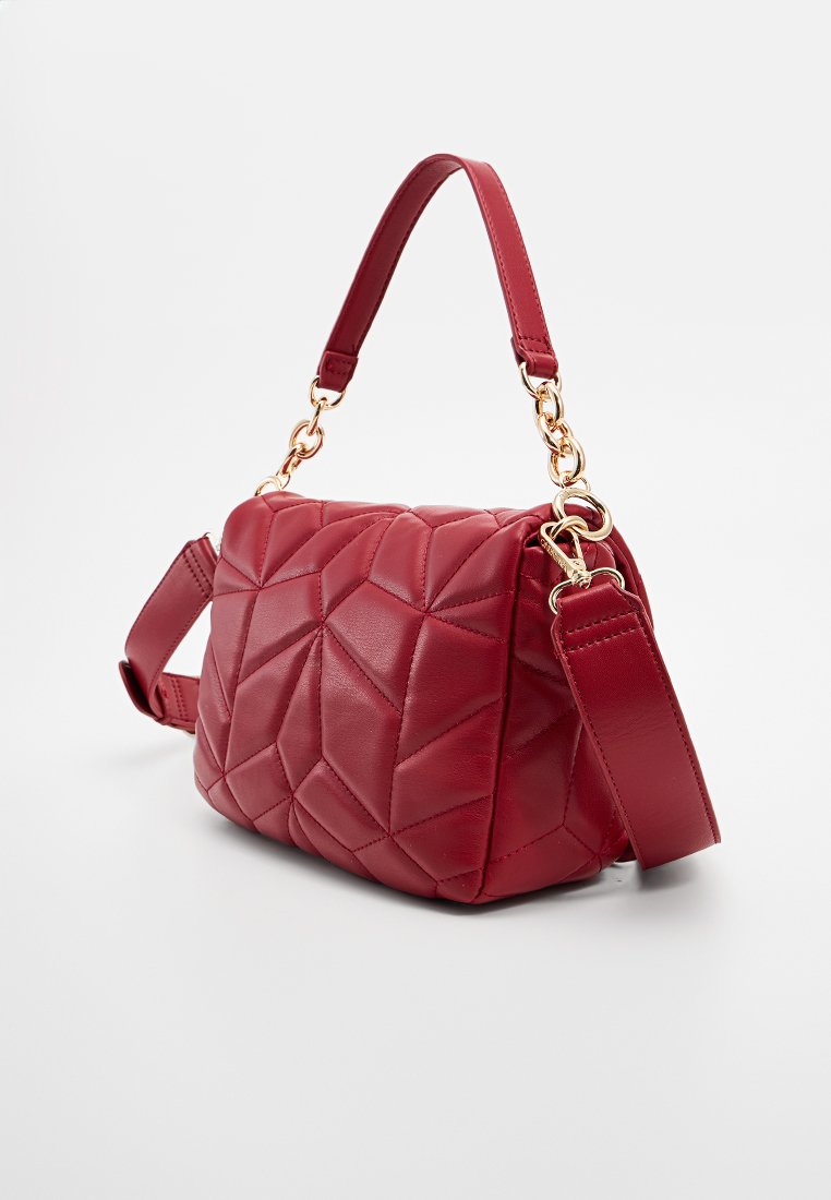 Bolso de piel acolchada roja con acentos de cadena dorada, asa superior y correa de hombro desmontable sobre fondo blanco liso.