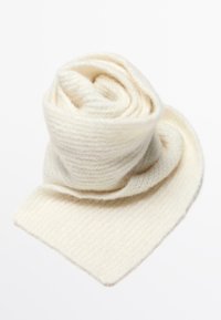 Una morbida sciarpa lavorata a maglia, di colore crema, arrotolata in una spirale, che mostra una texture a coste e un tessuto soffice su uno sfondo bianco.