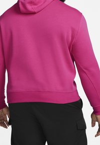 Růžová mikina s kapucí na stažení, měkkou texturou a žebrovanými manžetami, kombinovaná s černými cargo kalhotami s bočními kapsami.