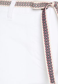 Hvide shorts med et vævet bælte med et herringbone-mønster i marineblå, rød og creme. Glat stof med synlige syninger.