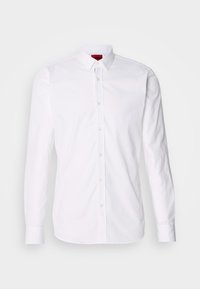Camisa blanca de manga larga con botones, que presenta un cuello clásico, tapeta delantera con botones y una textura suave de algodón.