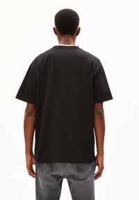 Black cotton t-shirt with short sleeves, round neckline, and a relaxed fit. Features a smooth texture and a solid color design.