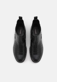 Botines negros con textura de cocodrilo brillante, paneles laterales elásticos y tiradores en la parte posterior, con un diseño de puntera redonda.