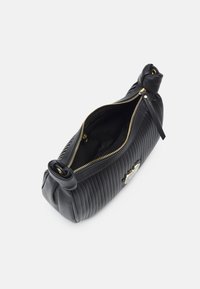 Černá prošívaná kožená kabelka se zlatým zipem, zaobleným vrchem s uzlíkovými konci a lesklým detailem na boku.