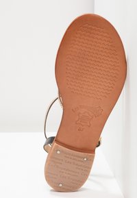 Sole di sandalo in cuoio marrone con un motivo testurizzato, caratterizzata da un logo di marca e dettagli sulle taglie impressi sul fondo.