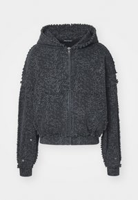 Black hoodie with zip closure, textured fabric, white abstract pattern, and frayed edges at sleeves and hem. Features a drawstring hood.