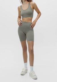 Sportig träningsklädesset i dämpad olivgrön, med en åtsittande crop top och högmidjade shorts, tillverkade av slät, stretchig tyg.