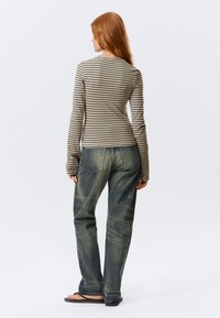 Gestreepte top met lange mouwen in aardetinten, gecombineerd met vervaagde blauwe denim jeans, met een relaxte pasvorm en een standaard achterzakontwerp.