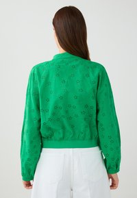 Groene geborduurde jas met bloemmotieven, lange mouwen en een fitted zoom; gemaakt van lichtgewicht stof, met een kraag.