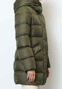 Opgeblazen olijfgroene jas met een hoge kraag, drukknoopsluiting en zijzakken. De textuur is glanzend met doorgestikte patronen over het hele oppervlak.