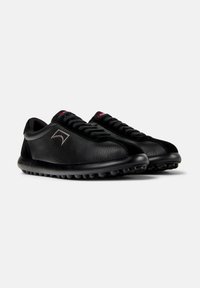 Sneaker in pelle nera con finitura testurizzata, dotati di punta rotonda, lacci neri e suola flessibile con piccoli rilievi per una migliore aderenza.