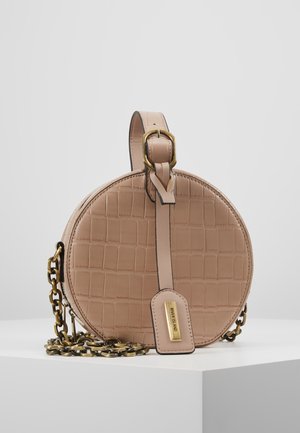 Sac à main rond beige à motif crocodile, boucle dorée, bandoulière chaîne et étiquette avec l'inscription River Island sur une surface blanche.