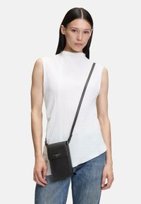 Sac à bandoulière noir avec une texture lisse, de forme rectangulaire et une fermeture à rabat. Il est doté d'une bandoulière et d'un détail de logo.