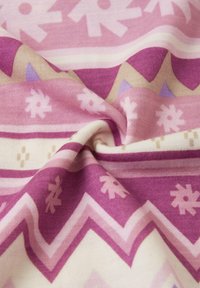 Strickstoff in Rosa- und Cremetönen mit geometrischen Mustern, einschließlich Zickzacklinien und floralen Motiven in Violett- und Beigetönen.
