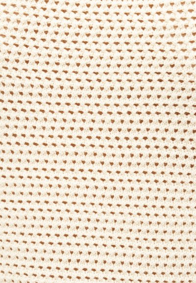 Πλεκτό ύφασμα σε κρεμ χρώμα με μικρό, επαναλαμβανόμενο μοτίβο που μοιάζει με βάφλα, δημιουργώντας υφασμάτινα τετράγωνα.