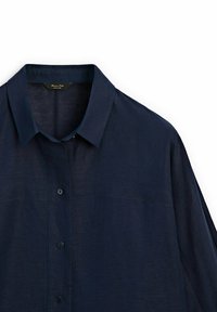 Chemise en lin bleu marine avec col, fermeture à boutons sur le devant et manches longues. Présente une texture subtile et un design épuré.
