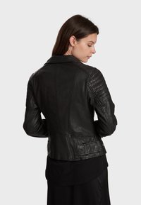 Veste de moto en cuir noir avec des panneaux ribbed sur les épaules et les bras. Design ajusté avec une taille cintrée et un col classique.