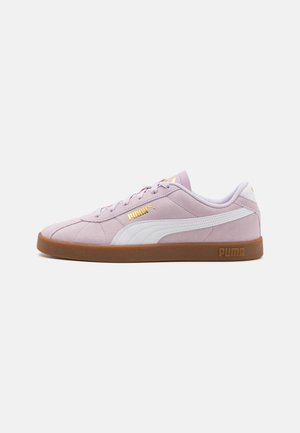 Jasnofioletowy sneaker Puma z białym paskiem, gumową podeszwą, złotymi logo Puma po bokach i na języku, widziany od zewnętrznej strony.