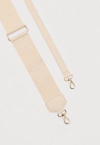 Correa ajustable para bolso de tela beige con broches giratorios dorados en ambos extremos y sutiles patrones en relieve de flores y círculos.