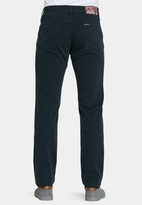 Pantaloni in cotone blu scuro con un design a gamba diritta; presentano due tasche posteriori e un'etichetta con il marchio sulla cintura. Scarpe con suola in gomma visibili.