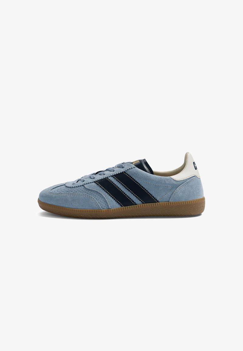 Baskets en daim bleu clair avec des bandes noires, semelle en gomme et languette blanche au talon, vues de côté sur un fond blanc.