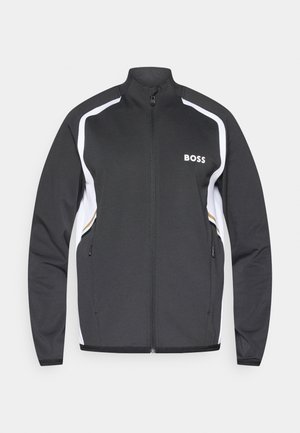 Jachetă sport neagră cu accente albe, guler înalt și fermoar frontal. Prezentă logo-ul "BOSS" pe pieptul stâng și buzunare laterale.