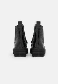 Botas Chelsea de charol negro con textura de cocodrilo, paneles laterales elásticos y tacones gruesos acanalados.