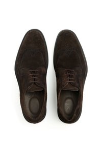 Dunkelbraune Wildleder-Herrenschuhe mit Flügelkappen-Design, Schnürverschluss und einem glatten Lederfutter. Flache Gummisohle mit leichter Struktur.