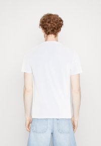 White short-sleeve T-shirt with a round neckline, made of smooth fabric. Simple design, no patterns or visible hardware. Casual fit.