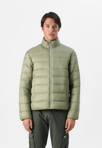 Lichtgroene, pufferjack met een hoge kraag, horizontale stiksels, volledige rits en een klein logo op de linkerborst.