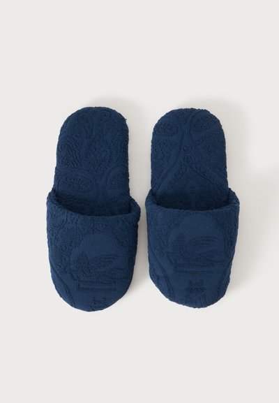 Paire de chaussons en tissu texturé bleu foncé avec bout fermé et dos ouvert, vue de dessus sur un fond clair.