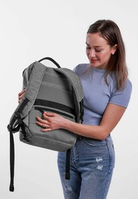 Šedý batoh s texturovaným designem, s přední kapsou na zip, nastavitelnými popruhy a pevným madlem, vystavený na bílém pozadí.