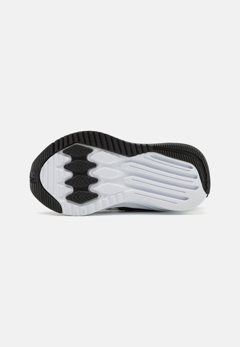 Suela de zapatilla deportiva en blanco y negro con un diseño texturizado, que presenta patrones de relieve y una sección central suave para mayor tracción.