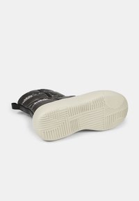 Black padded boots with a smooth finish, featuring a white rubber sole with textured grip patterns and a pull tab for easy wear.