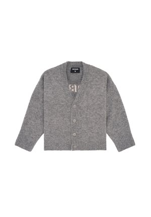 Cardigan gris en tricot à texture côtelée, avec de gros boutons, superposé à un haut noir, associé à un short noir et des mules à talons.
