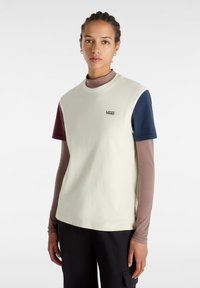 Camiseta de manga corta en crema, con mangas en azul marino y burdeos, cuello redondo y un pequeño logo negro en el pecho.