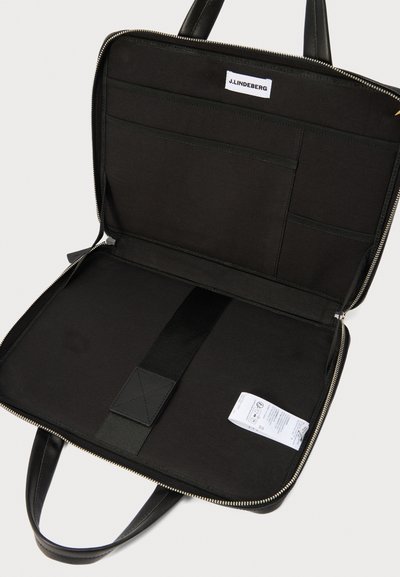 Μαύρη επαγγελματική τσάντα με φερμουάρ, ανοιχτή, που αποκαλύπτει πολλαπλές εσωτερικές θήκες, ελαστικό λουράκι, λευκή ετικέτα J. Lindeberg και λευκή ετικέτα με οδηγίες φροντίδας.